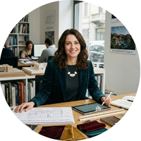 Sophia Rossi, Italian interior designer reviewing material samples and hotel blueprints in her studio. She partners with George Group for high-quality custom joinery and an extensive luxury material library.
